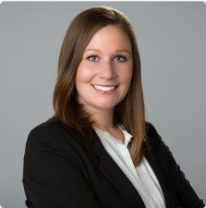A woman in a black jacket and white shirt is smiling for the camera.