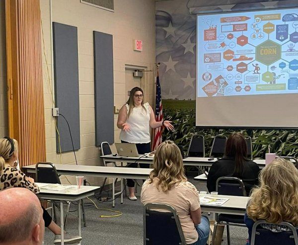 A woman is giving a presentation to a group of people in a room.