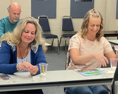 Two women are sitting at a table playing a game.