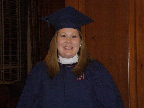 A woman wearing a graduation cap and gown is smiling for the camera.