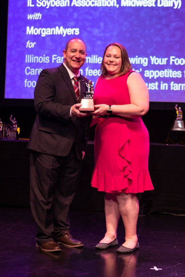 A man in a suit is holding a trophy next to a woman in a red dress