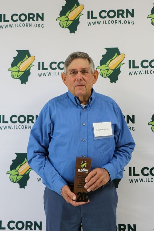 A man in a blue shirt is holding a plaque with the number 20 on it