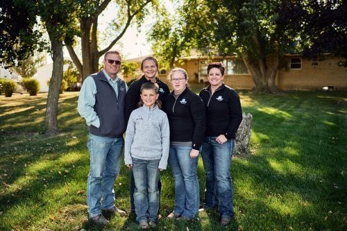 A family is posing for a picture in front of a house.