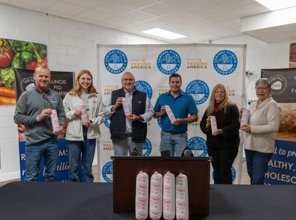 A group of people are standing around a podium holding sausages.