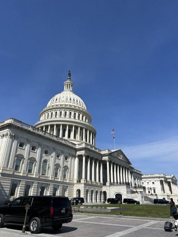 A car is parked in front of the capitol building.
