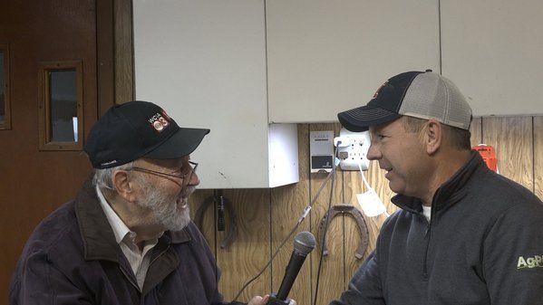 Two men are talking to each other in a kitchen with a microphone.