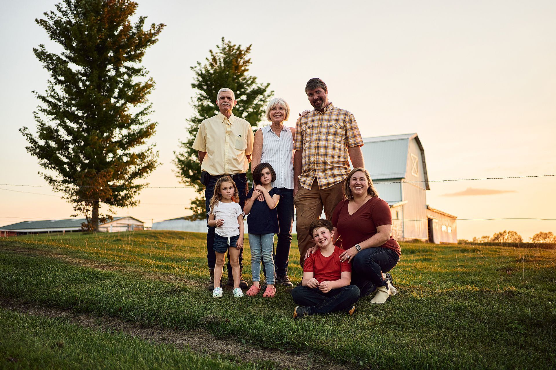 A family is posing for a picture in front of a barn.