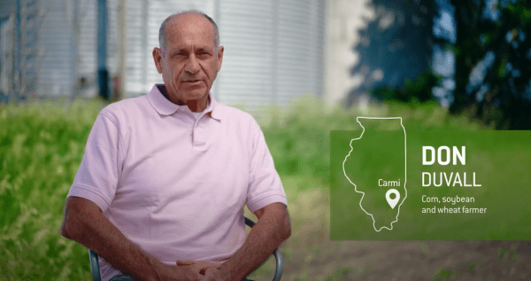 A man in a pink shirt is sitting in front of a map of illinois.