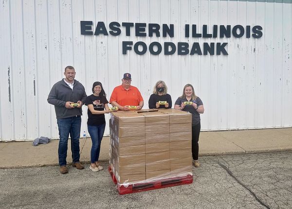 A group of people are standing in front of a large stack of boxes.