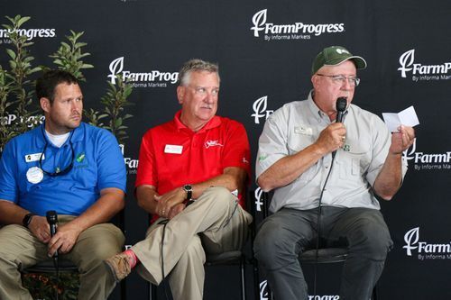 Four men are sitting in front of a wall that says farm progress