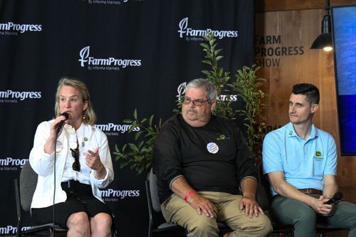 A woman is speaking into a microphone while sitting next to two men.