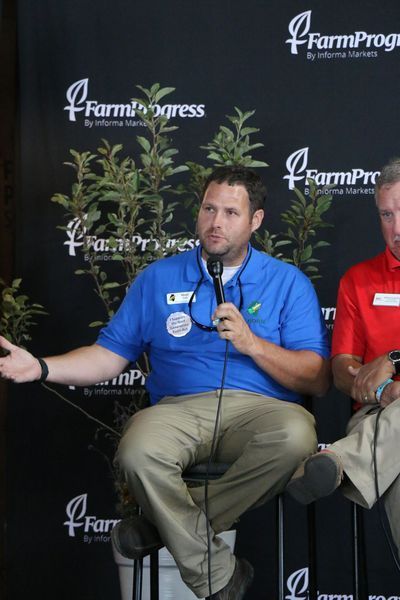 A man in a blue shirt is speaking into a microphone