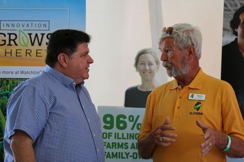 Two men are talking in front of a sign that says 96 % of filling farms are family owned