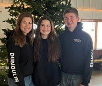 Three people are posing for a picture in front of a christmas tree.