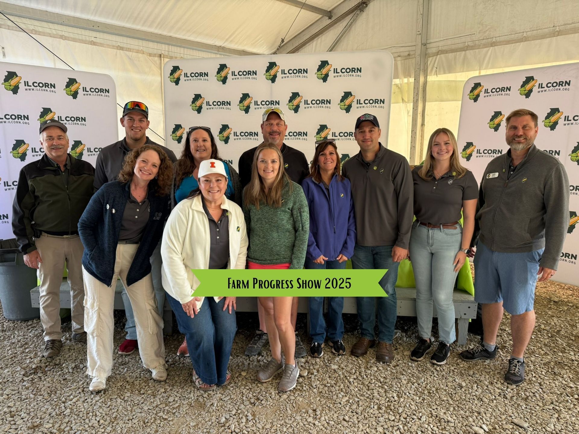 Group of people at an event with banners. Text on sign reads