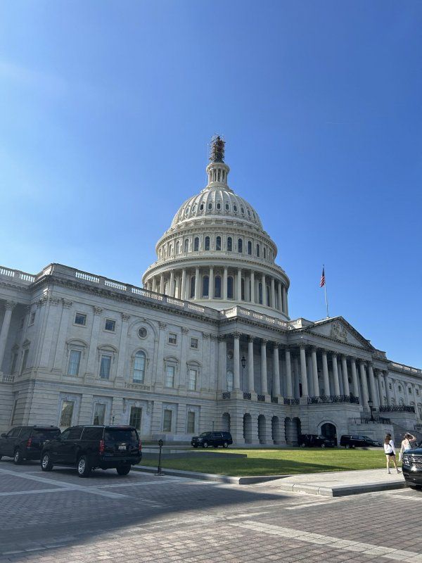 The capitol building in washington d.c. with cars parked in front of it.