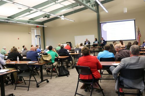 A large group of people are sitting at tables in a conference room.