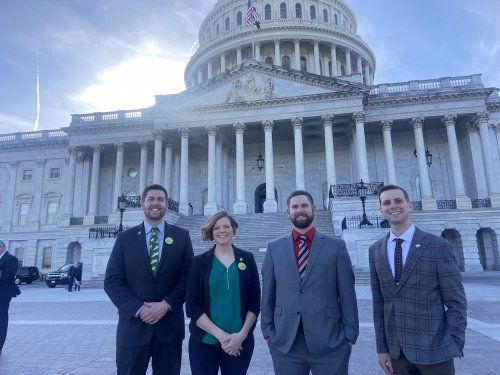 A group of people are standing in front of the capitol building.