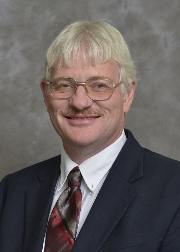 A man in a suit and tie is smiling for the camera