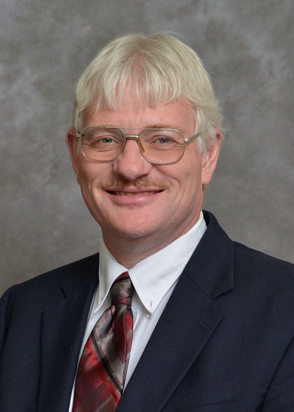 A man in a suit and tie is smiling for the camera