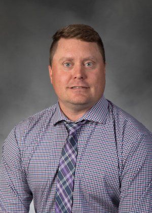 A man in a plaid shirt and tie is posing for a picture.