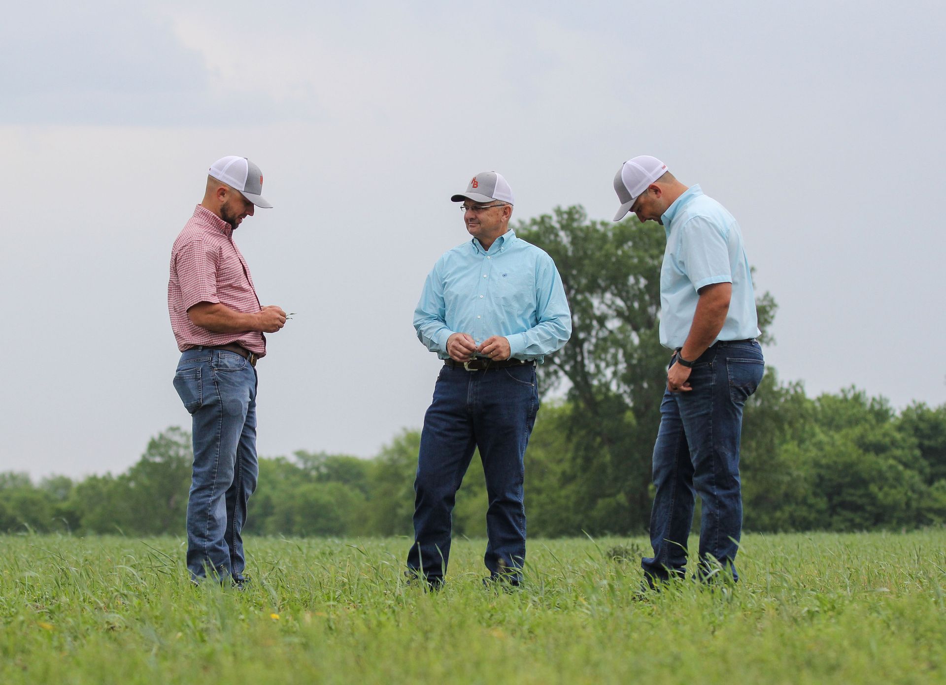 Three men are standing in a field talking to each other.
