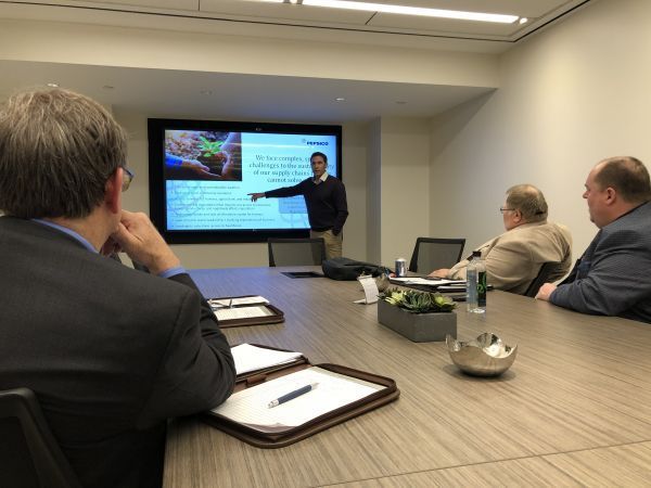 A man is giving a presentation to a group of people in a conference room