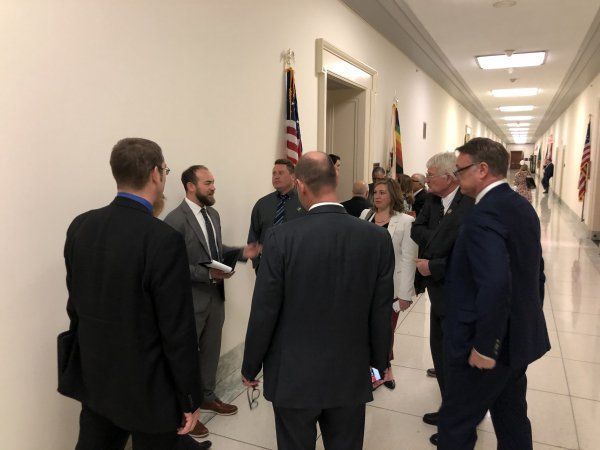 A group of people are standing in a hallway talking to each other