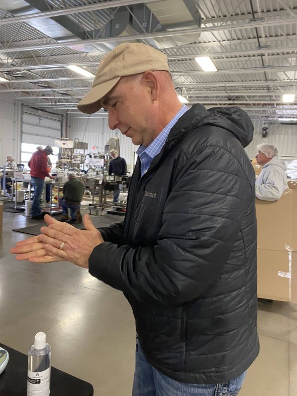 A man in a black jacket is washing his hands in a factory