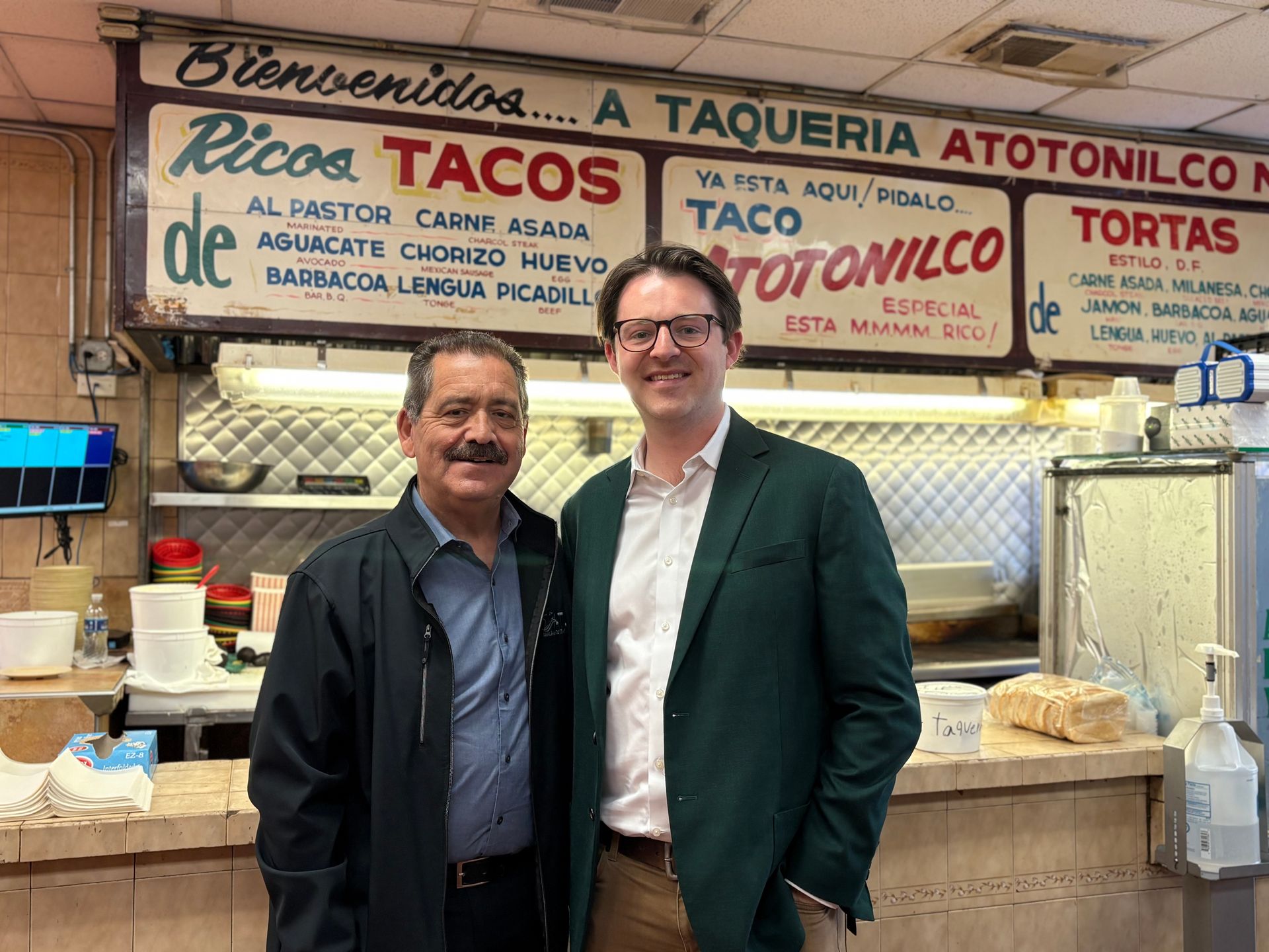 Two men are posing for a picture in a restaurant.
