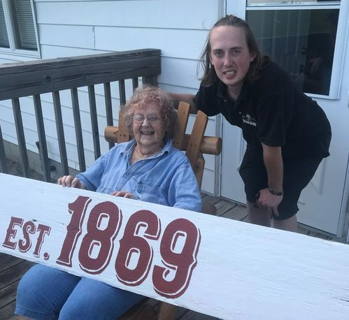 A man standing next to an elderly woman holding a sign that says 1869