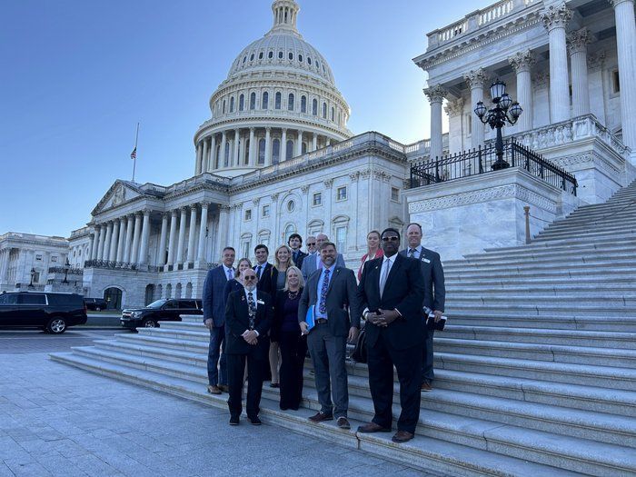 A group of people are standing on the steps of the capitol building.