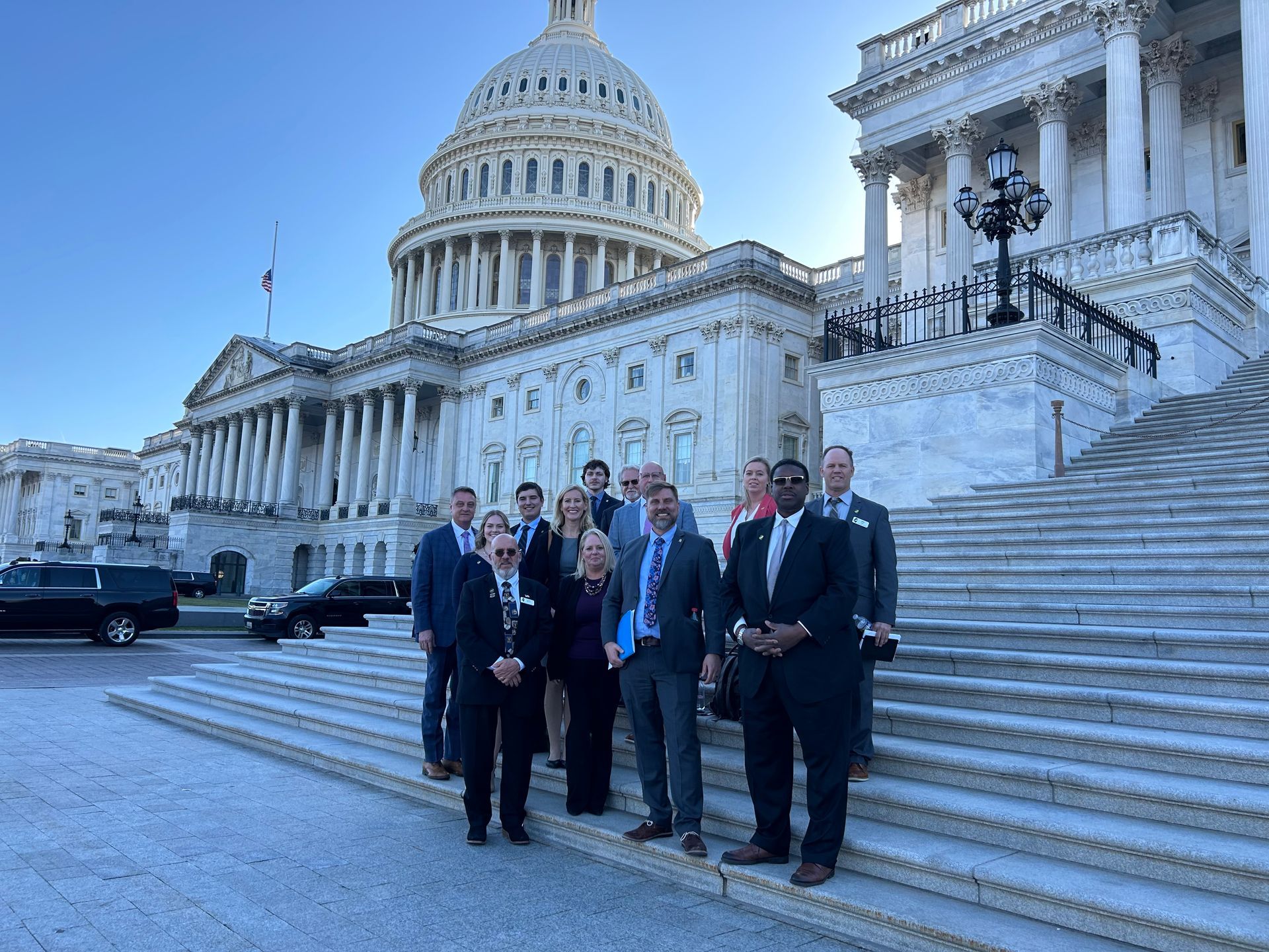 Group of people posing on steps in front of the U.S. Capitol building.