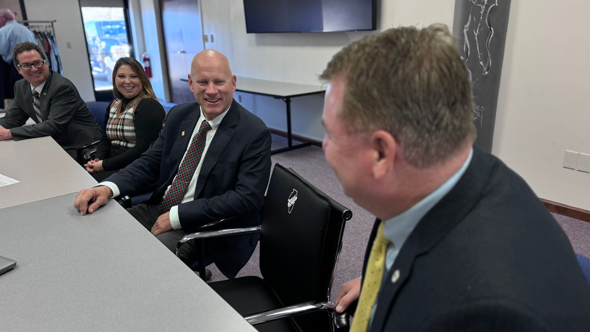 A group of people are sitting at a table in a conference room.
