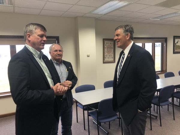 Three men are standing in a room talking to each other