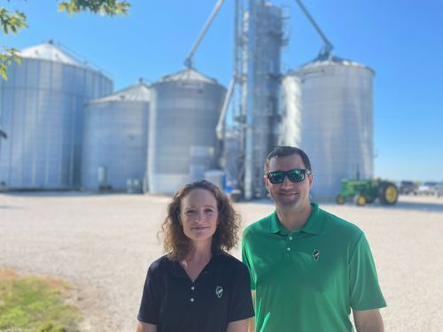 A man and a woman are standing in front of a grain silo.