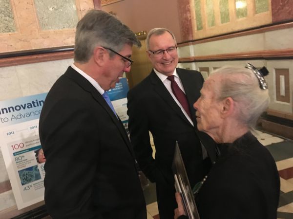 A man in a suit and tie is talking to an older woman