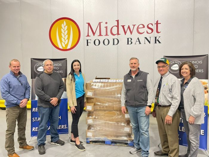 A group of people are standing in front of a midwest food bank sign.