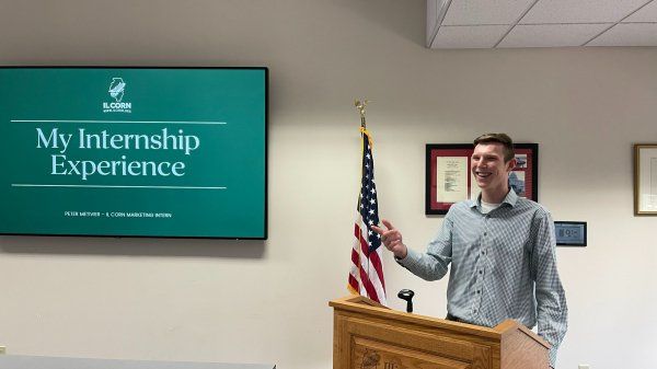A man is standing at a podium giving a presentation about his internship experience.