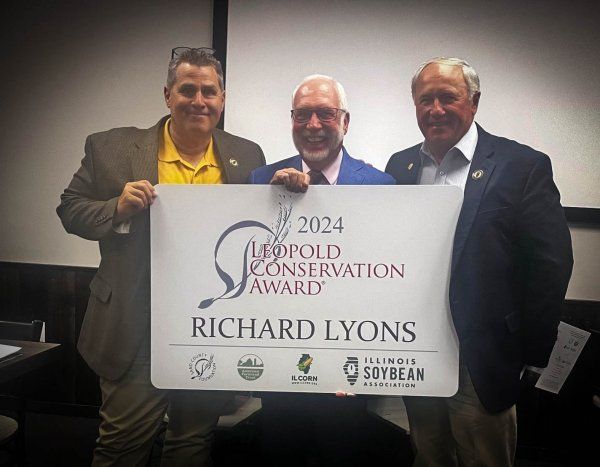 Three men holding a sign that says richard lyons