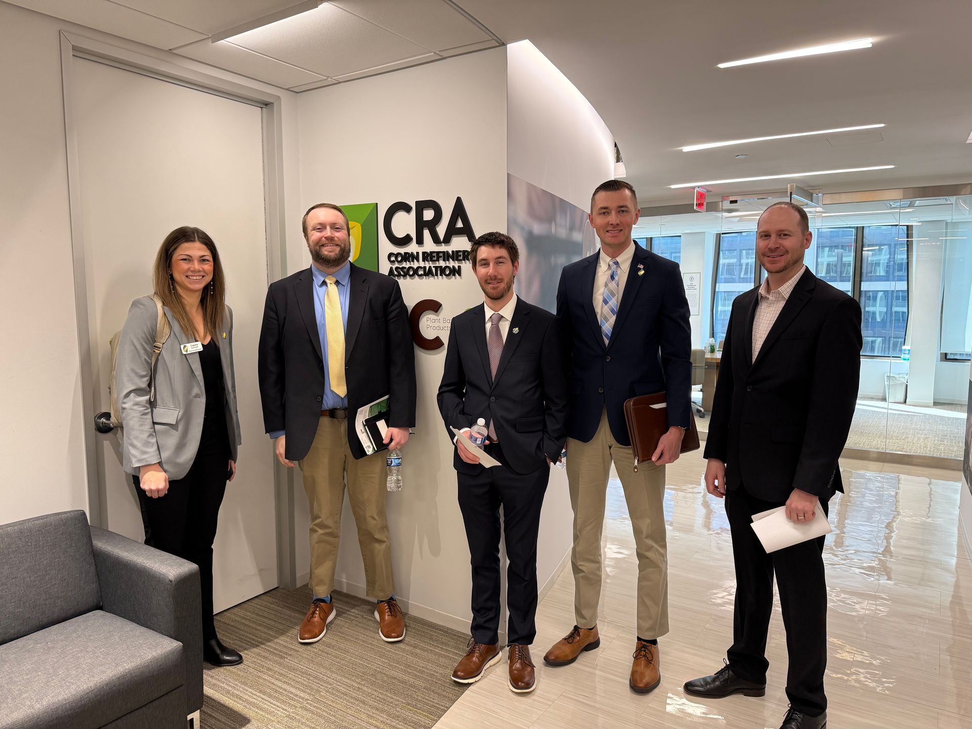 Five people stand in an office. A logo for