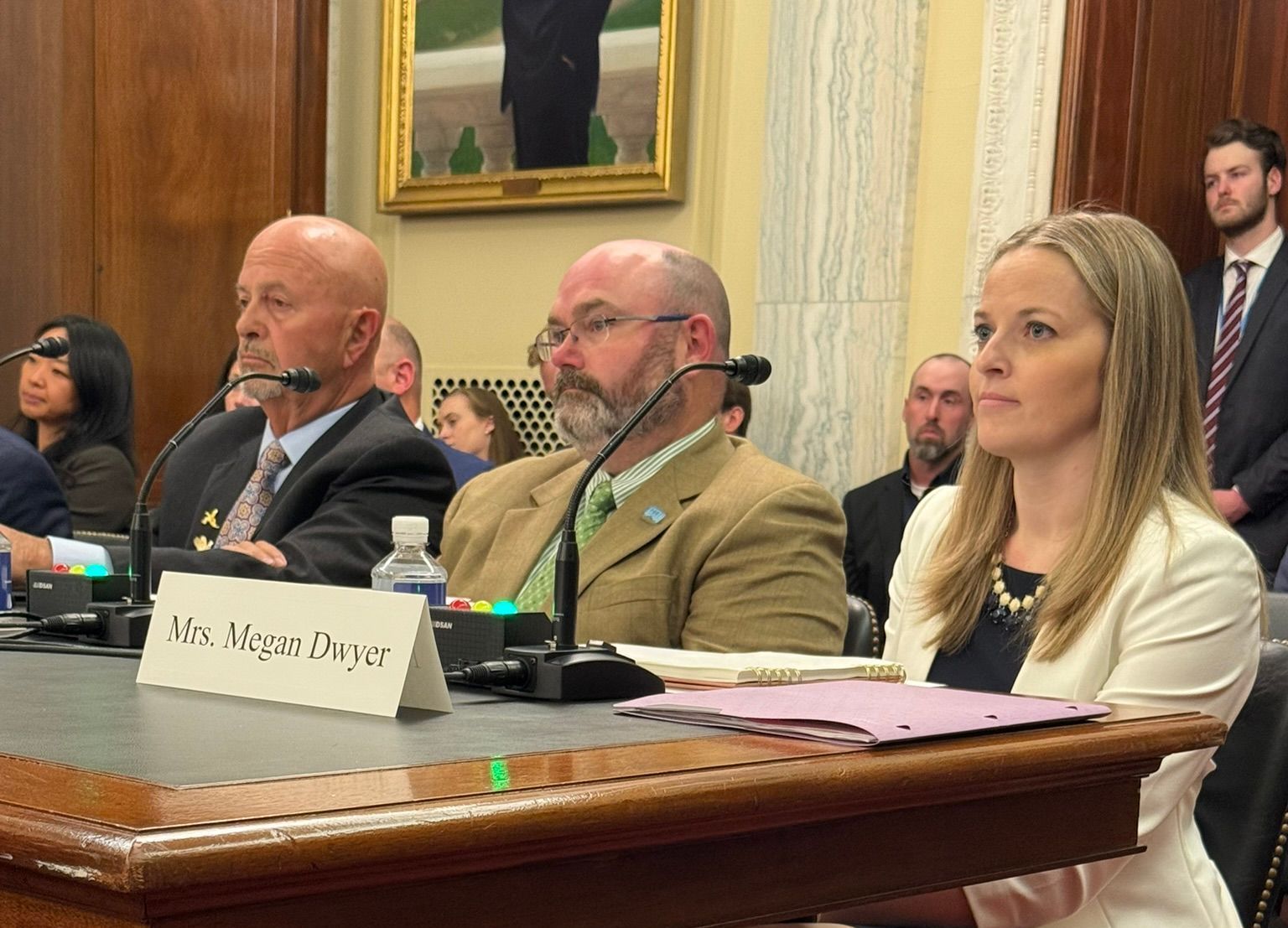 A group of people are sitting at a table in front of microphones.