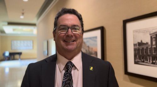 A man in a suit and tie is smiling in a hallway.