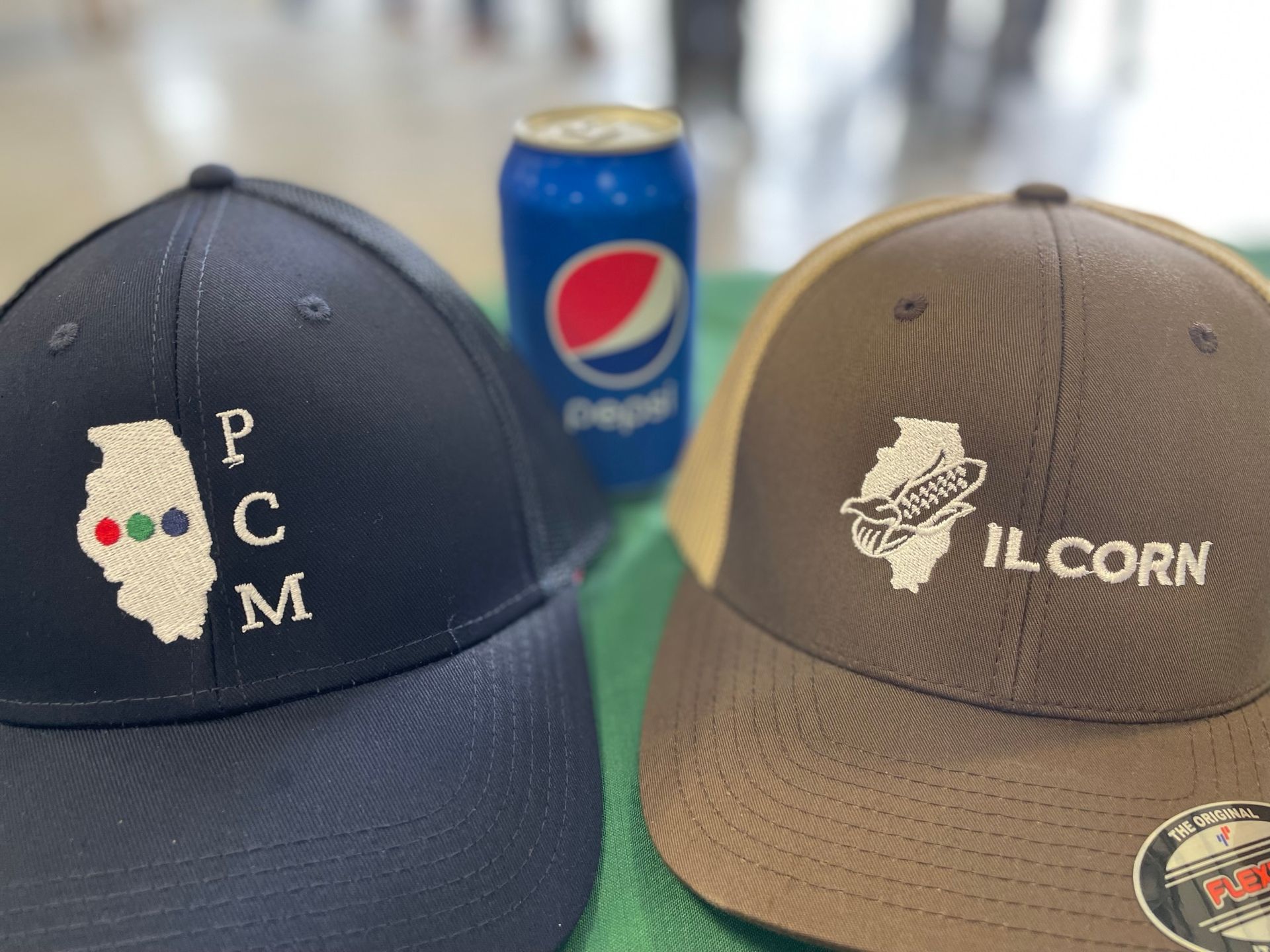Two hats are sitting on a table next to a can of pepsi