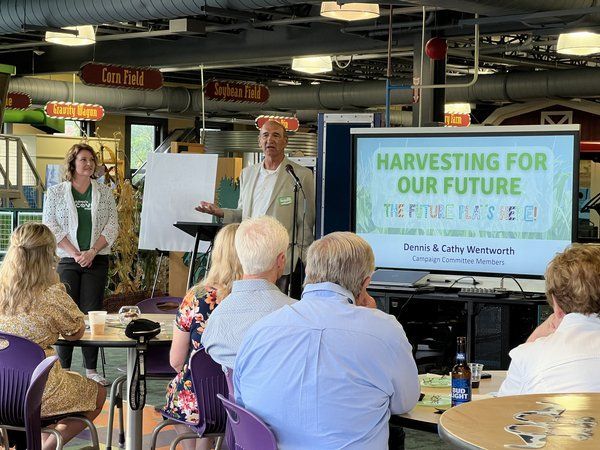 A man is giving a presentation to a group of people sitting at tables.