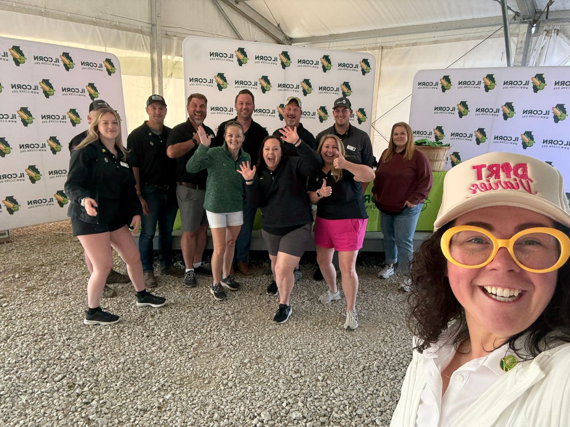 Group of people posing for a photo, some wearing hats and making silly faces. Inside a tent.