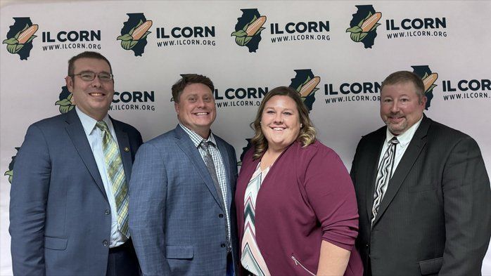 A group of people standing in front of a sign that says ilcorn