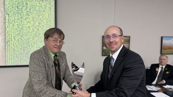 Two men in suits are shaking hands in a room.