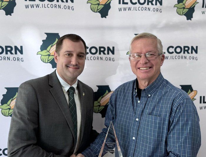 Two men shaking hands in front of a banner that says corn