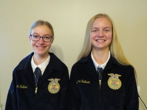 Two girls are posing for a picture and one of them is wearing glasses